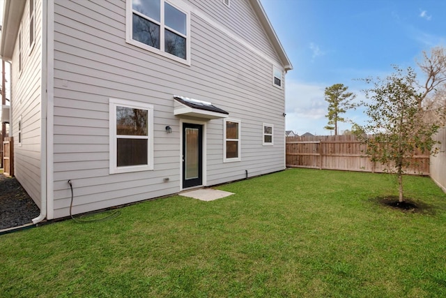 back of house featuring a fenced backyard and a yard