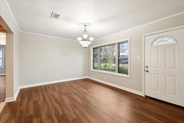 foyer entrance featuring visible vents, baseboards, a notable chandelier, wood finished floors, and crown molding
