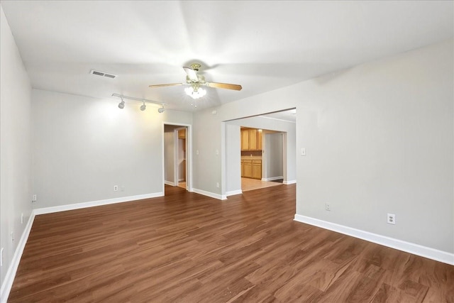 empty room featuring wood finished floors, visible vents, a ceiling fan, and baseboards