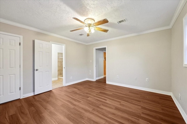 unfurnished bedroom with wood finished floors, visible vents, crown molding, and baseboards