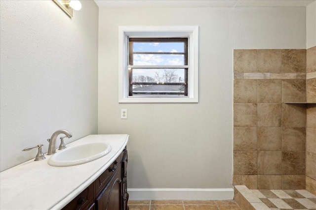 bathroom featuring baseboards, vanity, tile patterned floors, and a tile shower