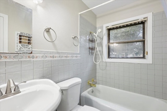 full bath with toilet, a sink, shower / tub combination, and tile walls