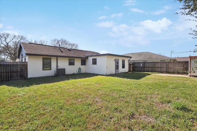 rear view of property with central air condition unit, a yard, and a fenced backyard