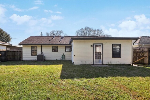 back of property with a yard, a fenced backyard, and central AC unit