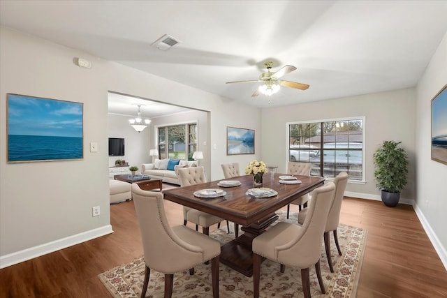 dining area with baseboards, wood finished floors, visible vents, and a healthy amount of sunlight