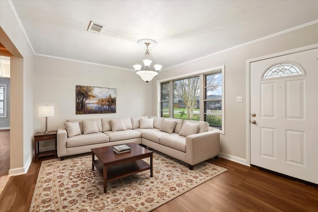 living area with ornamental molding, wood finished floors, and visible vents