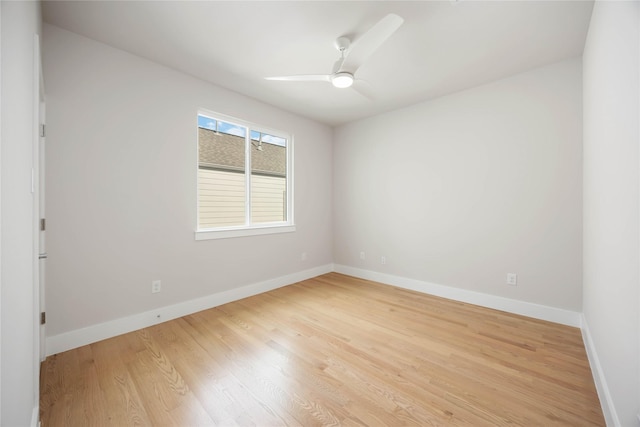 spare room featuring light wood finished floors, a ceiling fan, and baseboards