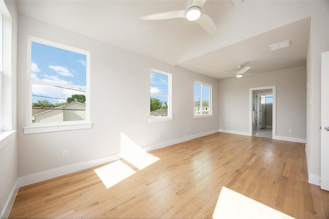spare room featuring baseboards, a ceiling fan, visible vents, and light wood-style floors