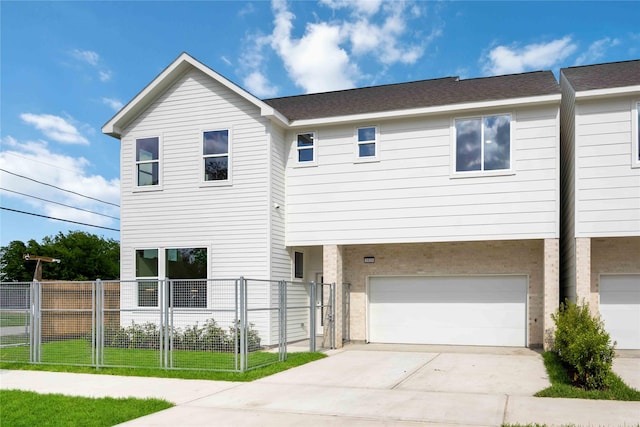 view of front of house with an attached garage, concrete driveway, and fence
