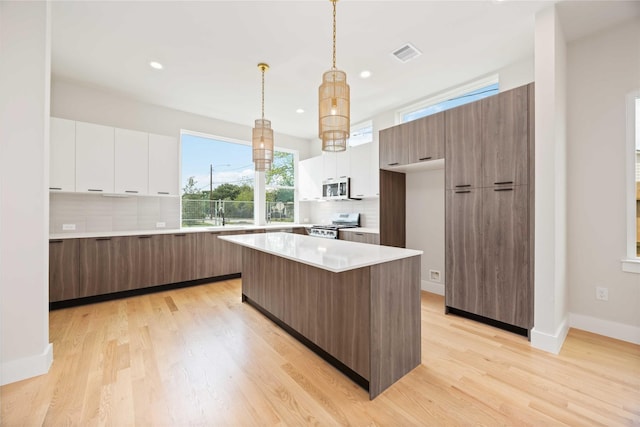 kitchen with modern cabinets, white cabinetry, stainless steel appliances, and visible vents