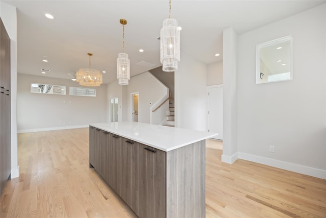 kitchen with light wood-type flooring, modern cabinets, baseboards, and an inviting chandelier
