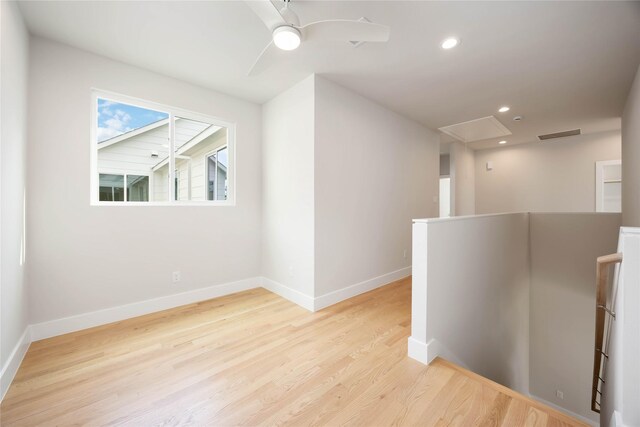 interior space with attic access, light wood-style flooring, visible vents, and baseboards