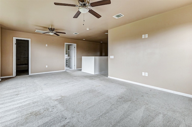 carpeted spare room with visible vents, a ceiling fan, and baseboards