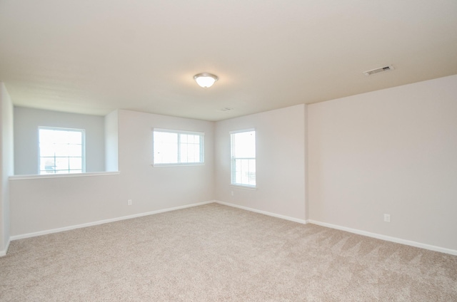 empty room with baseboards, carpet floors, visible vents, and plenty of natural light