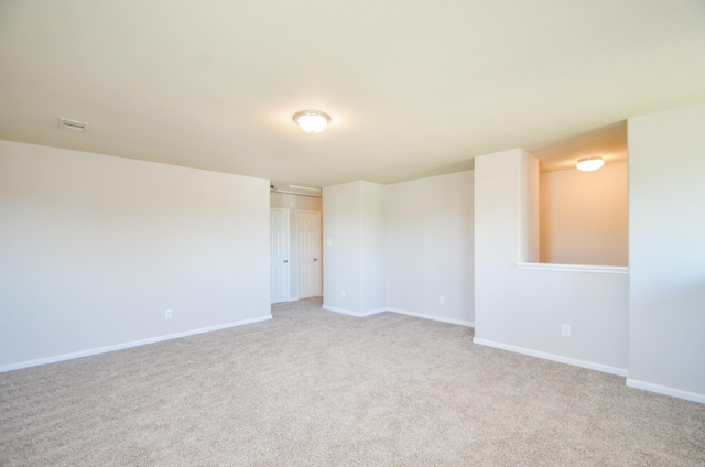 spare room with baseboards and light carpet