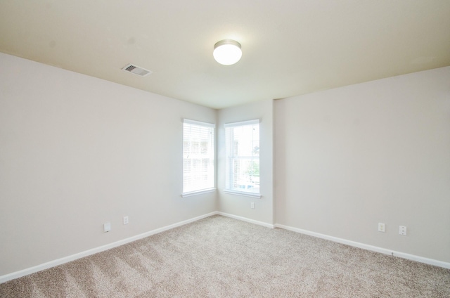 carpeted empty room featuring baseboards and visible vents