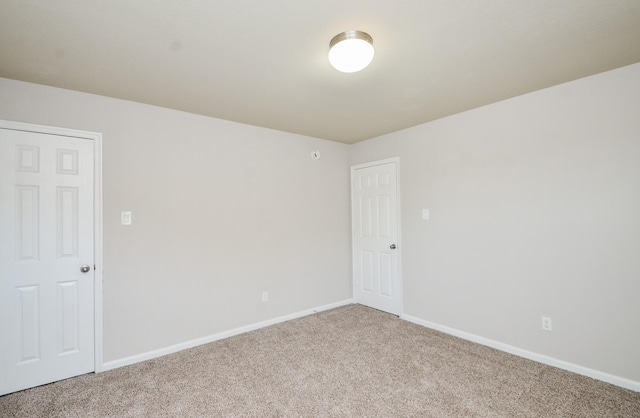 unfurnished room with baseboards and light carpet