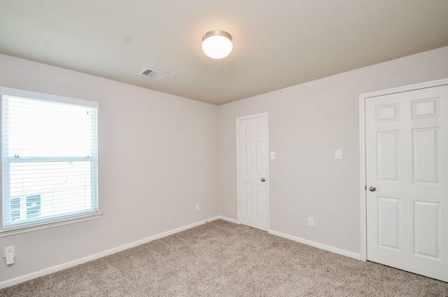 spare room featuring visible vents, baseboards, and light carpet