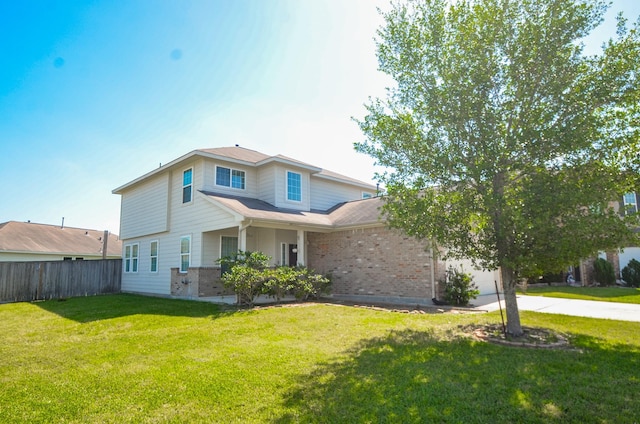 traditional-style home with concrete driveway, fence, a front yard, a garage, and brick siding