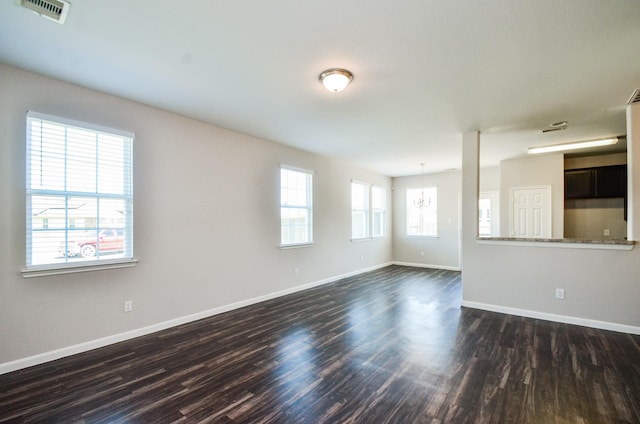 unfurnished room featuring baseboards, visible vents, and dark wood-type flooring