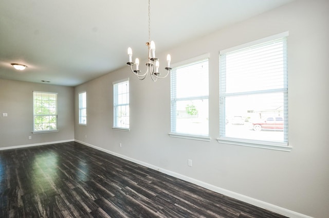 empty room featuring baseboards, dark wood-style floors, and a chandelier