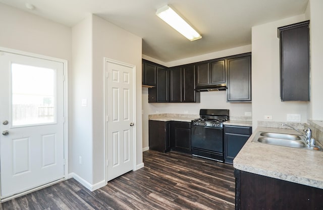 kitchen with a sink, dark wood-style flooring, black gas stove, light countertops, and under cabinet range hood