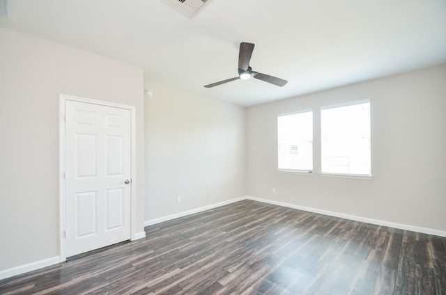 spare room featuring dark wood finished floors, visible vents, and baseboards