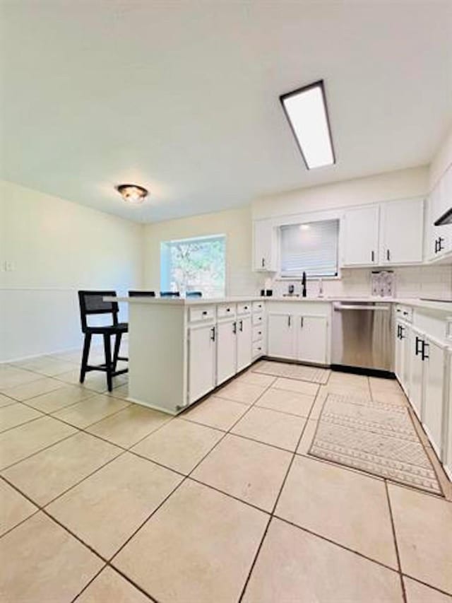 210 Glenbrook St, Vidor, TX 77662 - kitchen featuring white cabinets, light countertops, stainless steel dishwasher, light tile patterned floors, and a peninsula