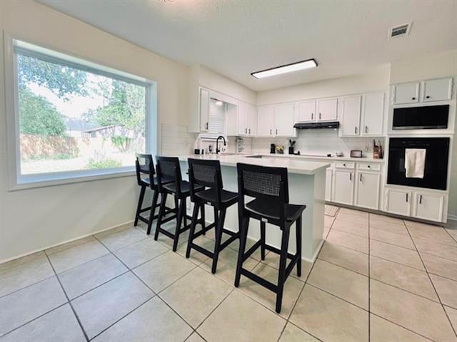 210 Glenbrook St, Vidor, TX 77662 - kitchen with tasteful backsplash, light countertops, under cabinet range hood, black oven, and visible vents