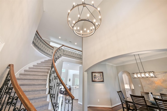 314 Del Monte Dr, Friendswood, TX 77546 - stairs with a towering ceiling, ornamental molding, arched walkways, baseboards, and a notable chandelier