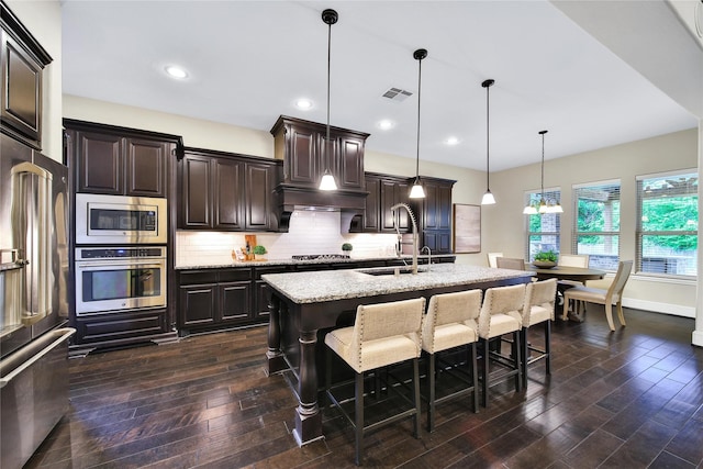 182 River Wilde Dr, Montgomery, TX 77316 - kitchen featuring stainless steel appliances, a sink, dark wood-type flooring, light stone countertops, and recessed lighting