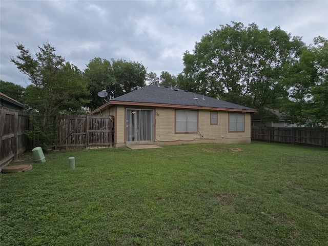 back of house with a lawn and a fenced backyard