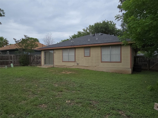 rear view of house featuring a fenced backyard and a yard