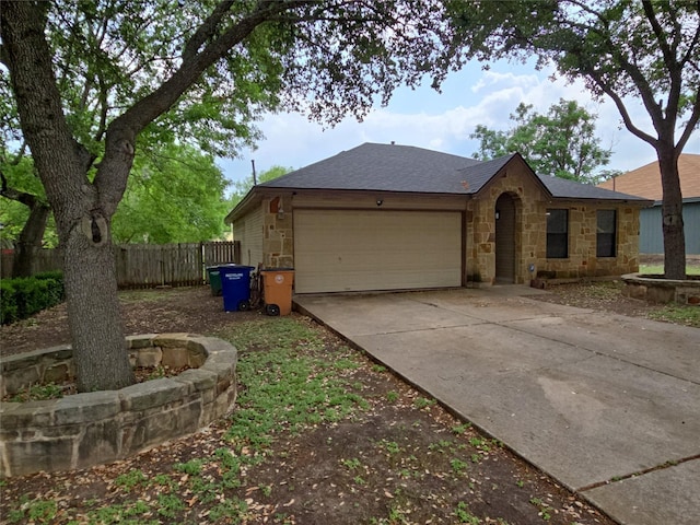 view of home's exterior with a garage, fence, stone siding, roof with shingles, and driveway