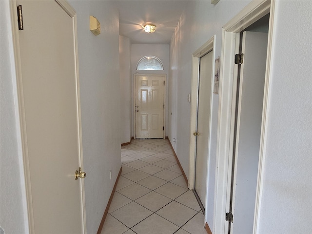 hall featuring light tile patterned floors and baseboards