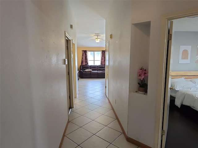 corridor featuring light tile patterned floors and baseboards