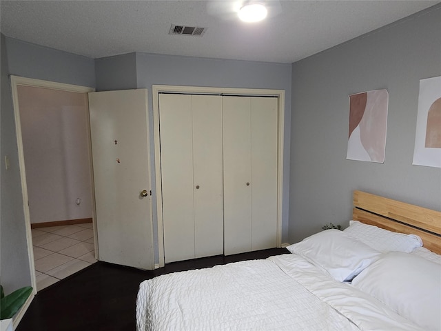 tiled bedroom featuring visible vents and a closet