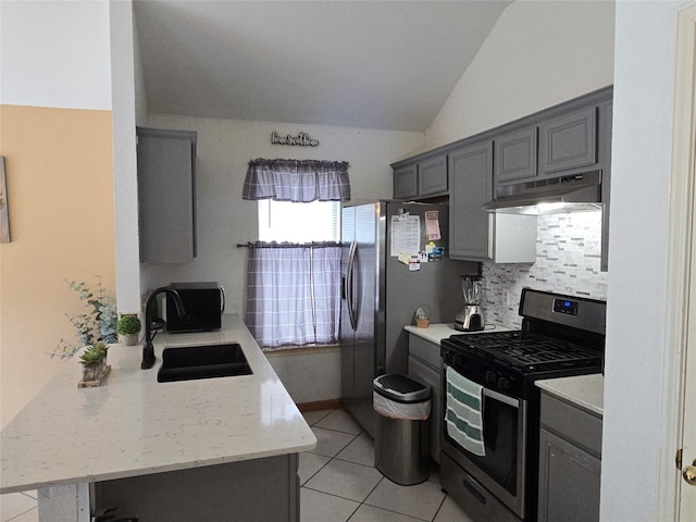 kitchen with under cabinet range hood, tasteful backsplash, a sink, appliances with stainless steel finishes, and light tile patterned floors
