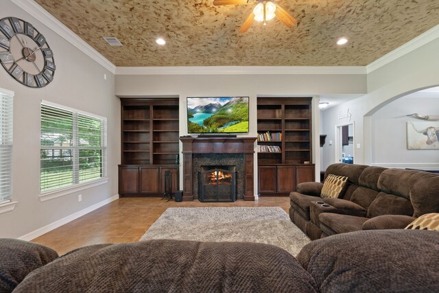 17111 Paluxy Ct, Splendora, TX 77372 - tiled living area featuring ceiling fan, a lit fireplace, arched walkways, crown molding, and baseboards