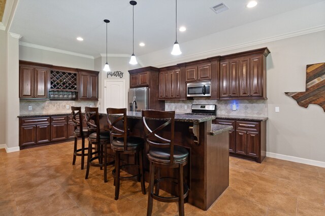 17111 Paluxy Ct, Splendora, TX 77372 - kitchen with appliances with stainless steel finishes, a kitchen bar, decorative backsplash, a kitchen island with sink, and dark brown cabinetry