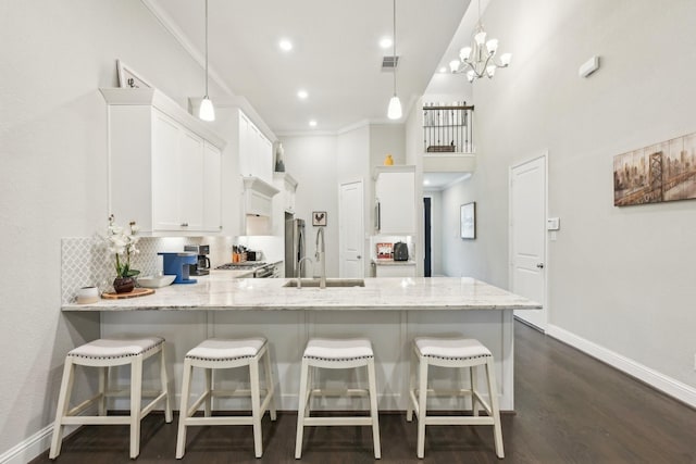 kitchen with light stone countertops, dark wood finished floors, a peninsula, white cabinetry, and baseboards