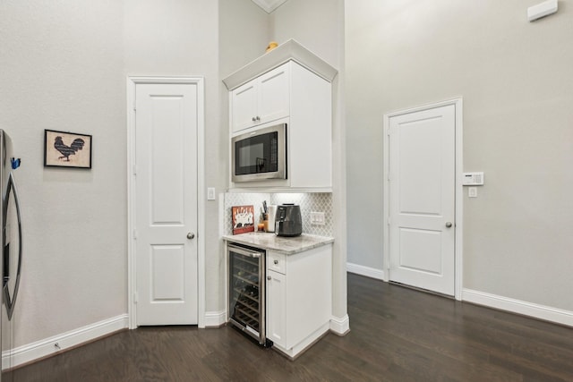 kitchen with dark wood-style flooring, built in microwave, baseboards, wine cooler, and white cabinetry