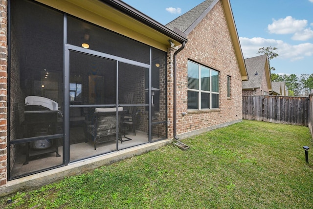 exterior space featuring fence, a lawn, and brick siding