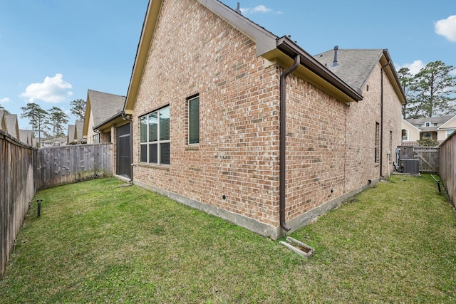 view of side of property with a yard, brick siding, central AC, and a fenced backyard
