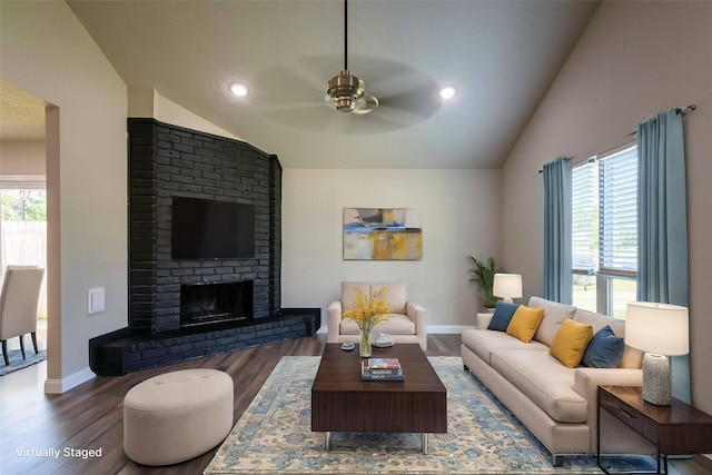 living room with lofted ceiling, wood finished floors, baseboards, a brick fireplace, and ceiling fan