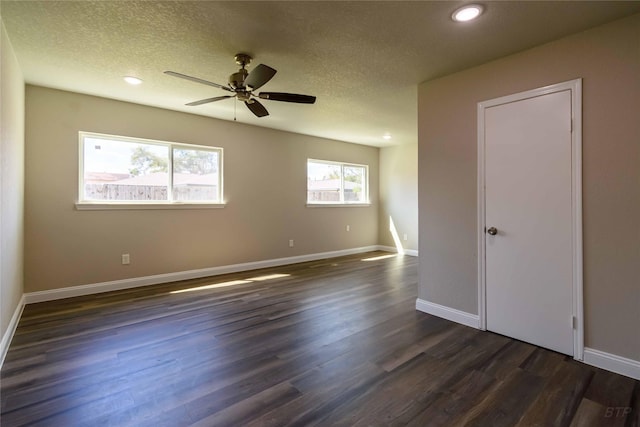 empty room featuring dark wood-type flooring, a textured ceiling, baseboards, and ceiling fan