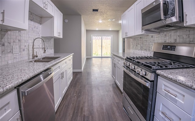 kitchen featuring white cabinets, stainless steel appliances, backsplash, a sink, and a textured ceiling