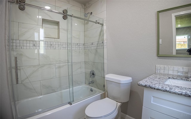 bathroom with toilet, a textured wall, vanity, and bath / shower combo with glass door