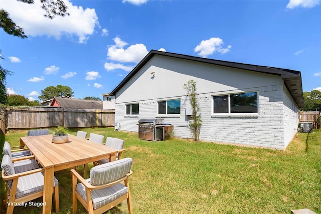 rear view of house with a lawn, fence, outdoor dining space, and cooling unit
