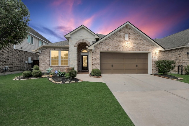 french country home with driveway, brick siding, a front yard, and a garage